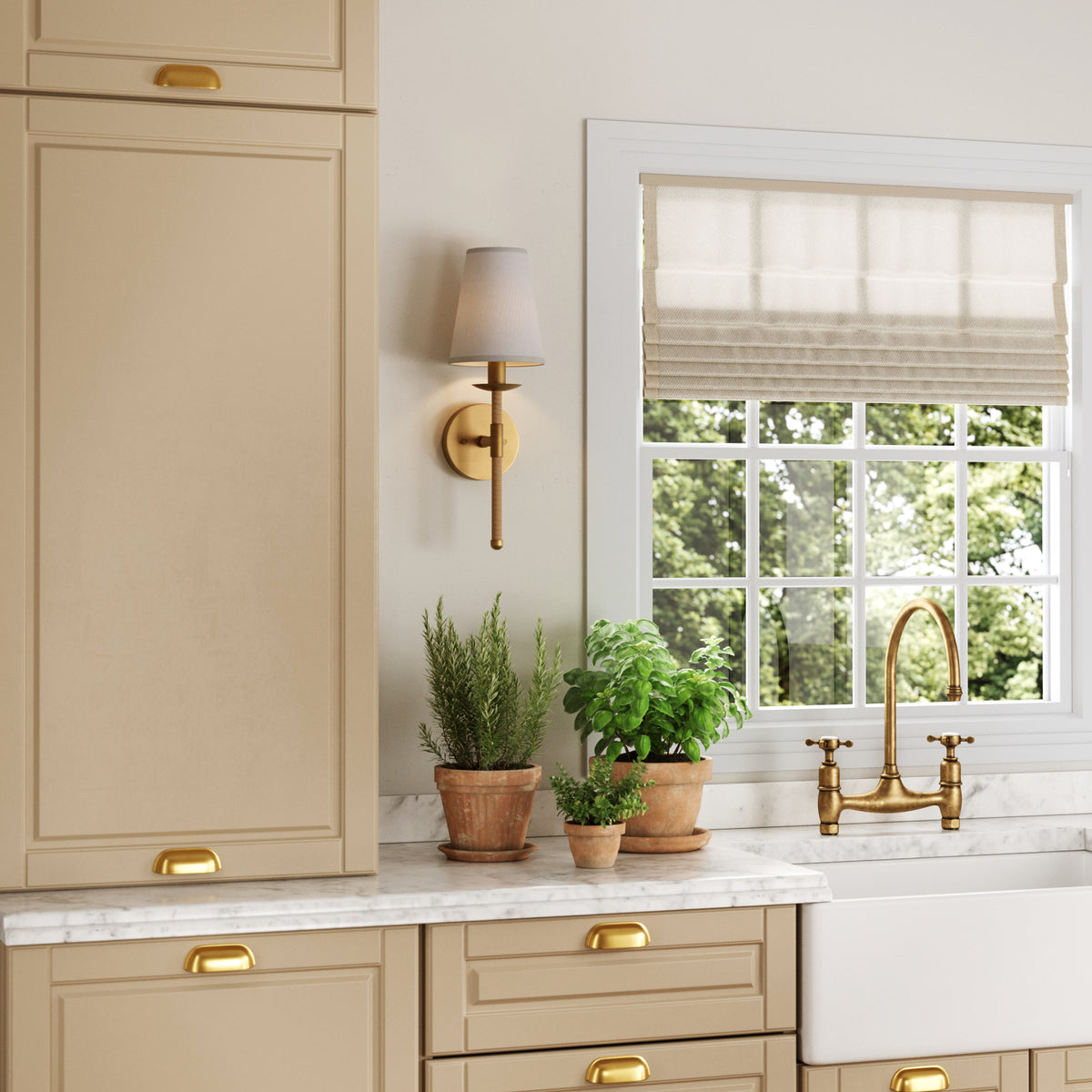A kitchen counter with beige cabinets, a marble backsplash, a farmhouse sink with a gold faucet, and three potted plants near a window with a fabric shade.