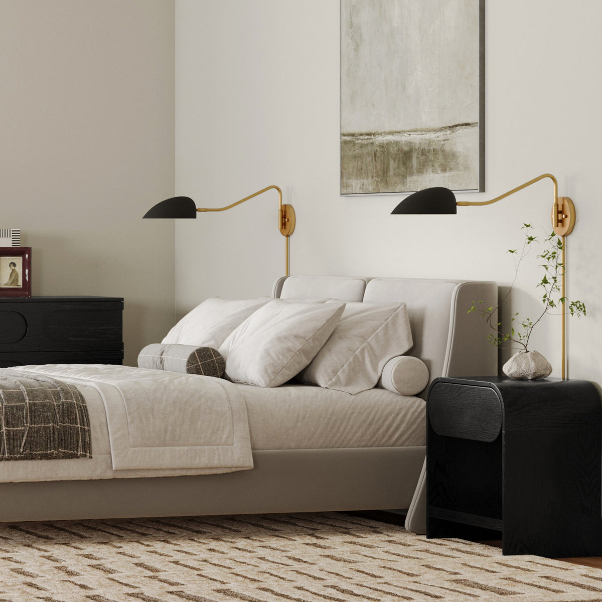 A bedroom featuring a light-colored upholstered bed with two black, gold-armed wall sconces and black bedside tables.