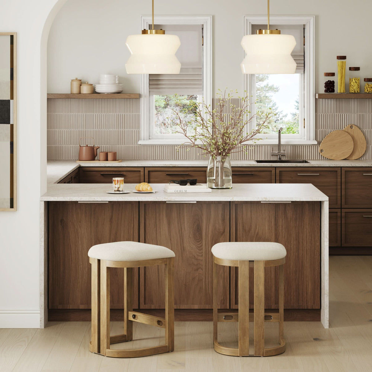 Two Nathan James Barrel Wooden Backless Bar Stool Light Brown (Set of 2) with circular, light-colored upholstered seats positioned in front of a kitchen island.