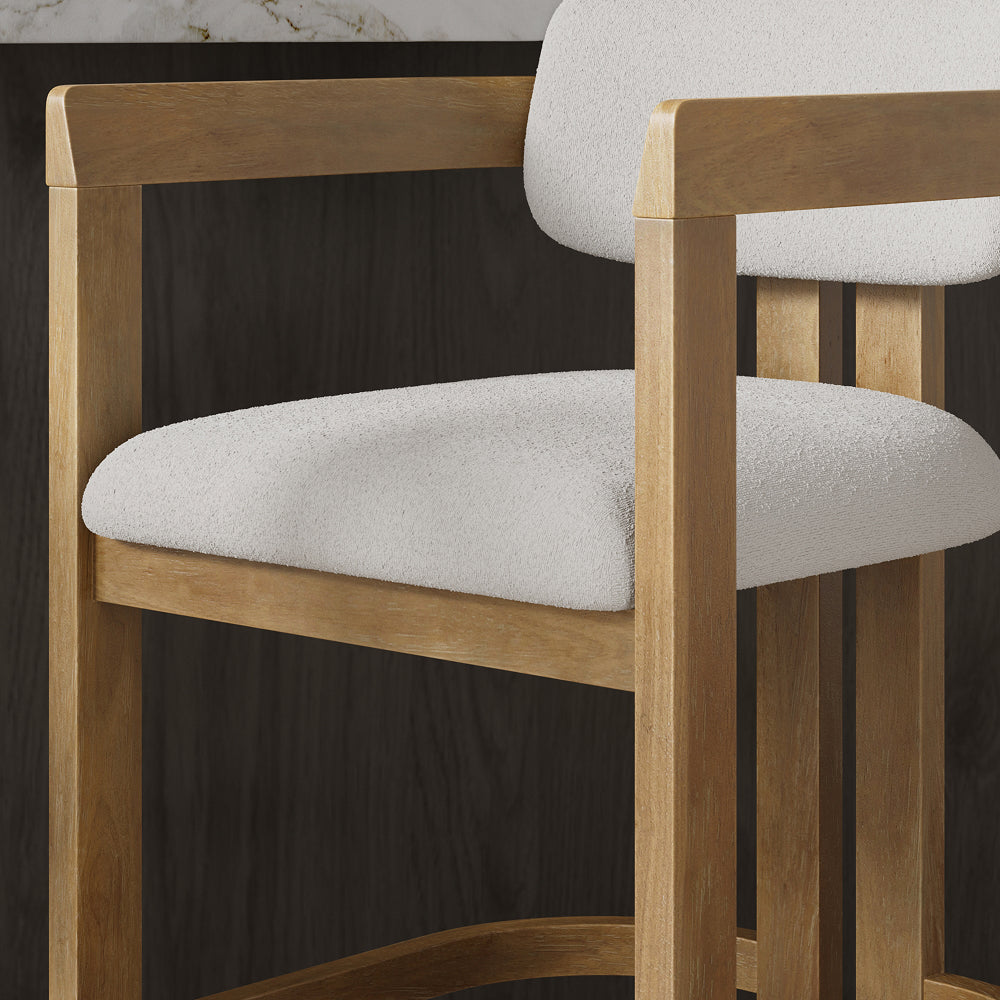 Wooden bar stool with a light-colored, textured upholstered seat and backrest.