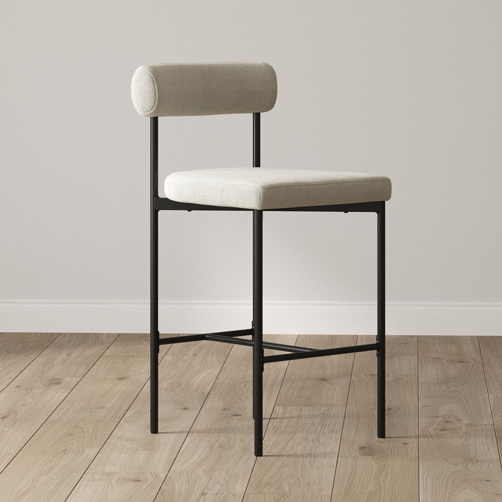 Counter stool with a black metal frame and light-colored upholstered seat and cylindrical backrest.