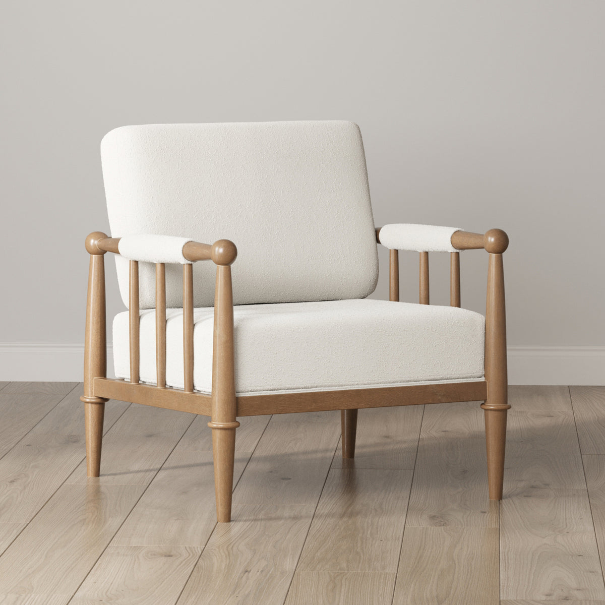 An armchair with a light-colored upholstered seat and back, featuring a spindle-style wooden frame and armrests.
