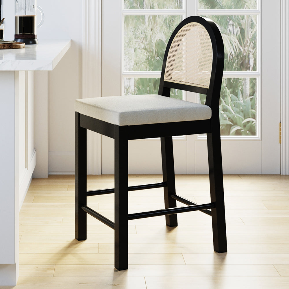 Counter stool with a black wooden frame, light-colored upholstered seat, and an arched rattan backrest.