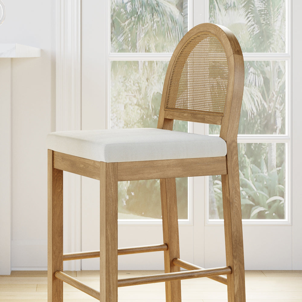 Light wood bar stool with a rounded cane back and an upholstered white seat.