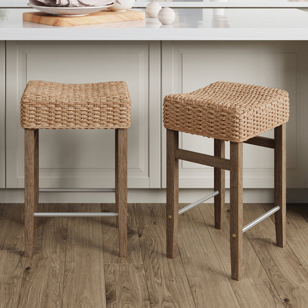 Two backless bar stools with woven tan seats and wooden legs featuring metal footrests.