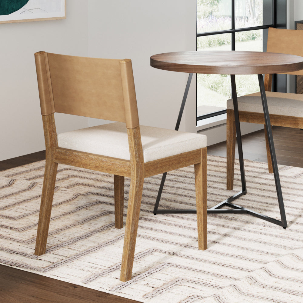 A wooden dining chair with a light tan leather backrest and a beige upholstered seat, positioned near a small round table.