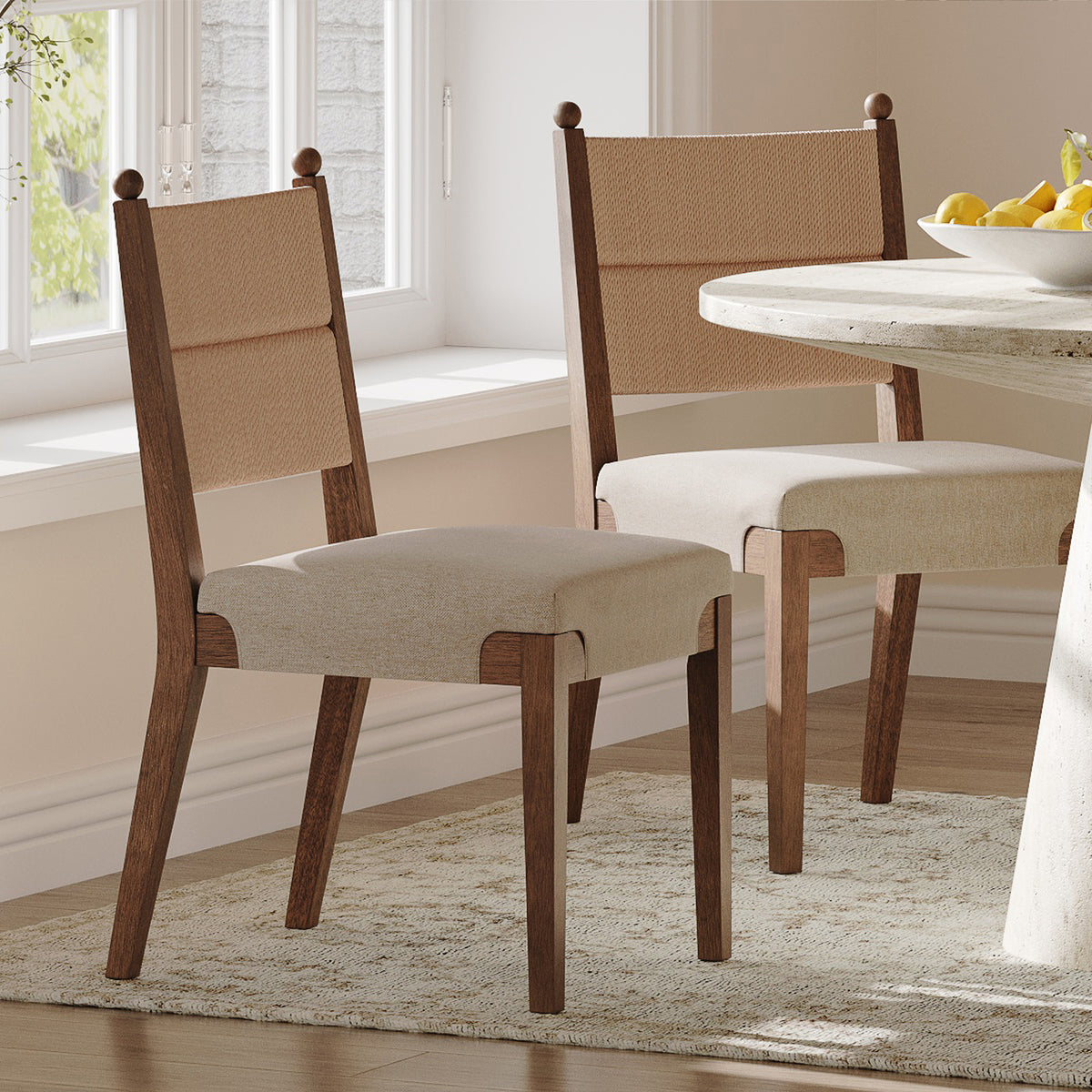 Two wooden dining chairs with woven backrests and upholstered seats placed at a round table.