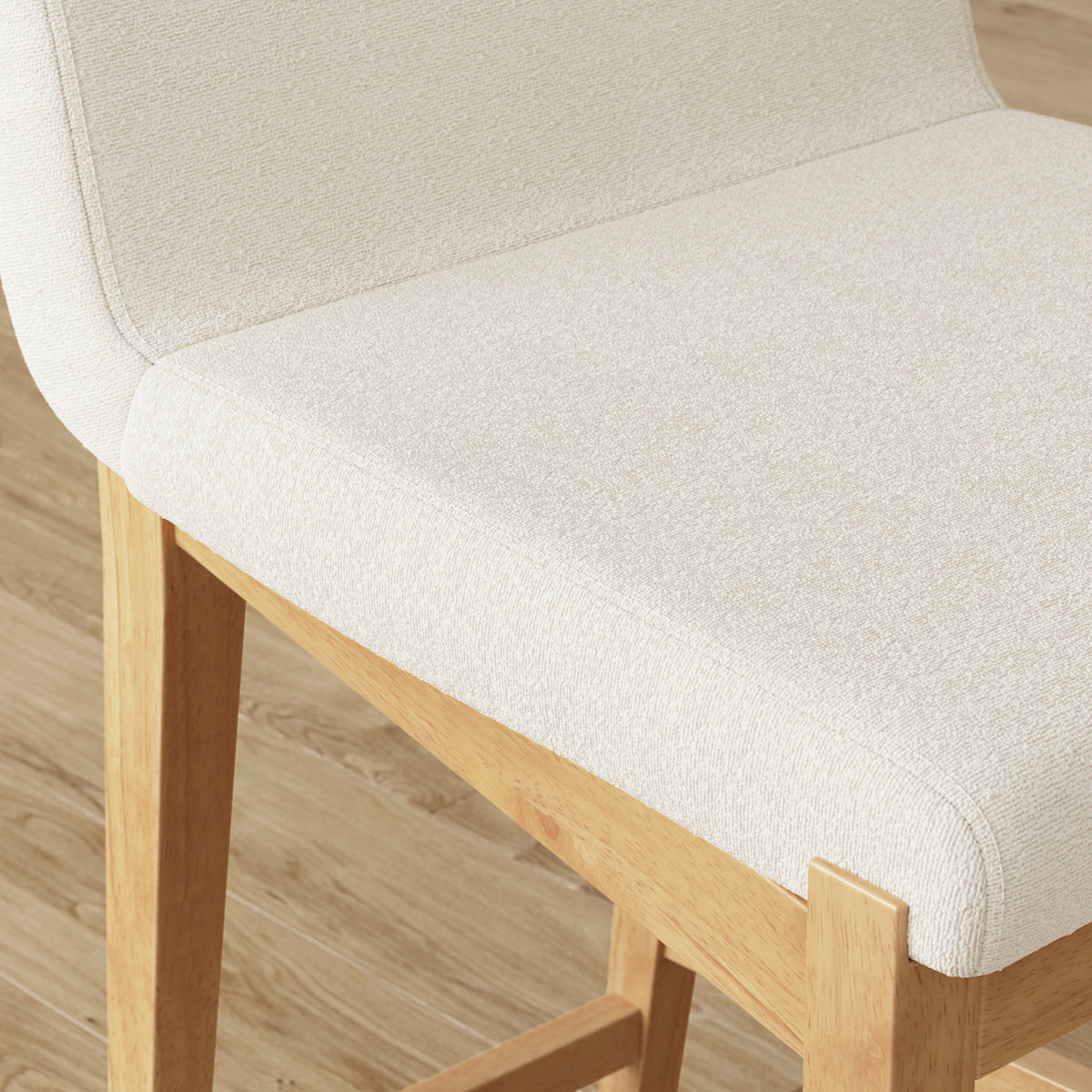 Off-white upholstered dining chair with wooden legs.