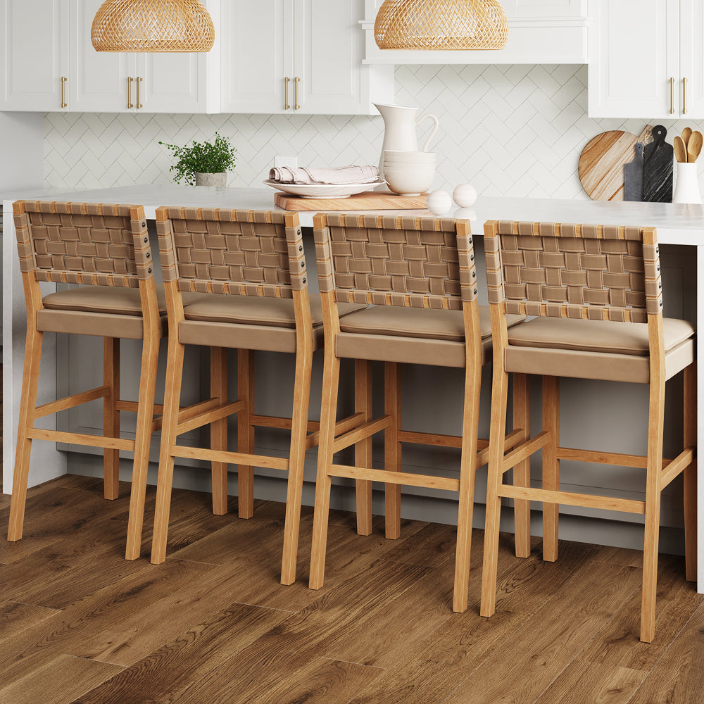 Four wooden bar stools with woven tan backs and upholstered seats lined up at a kitchen island.