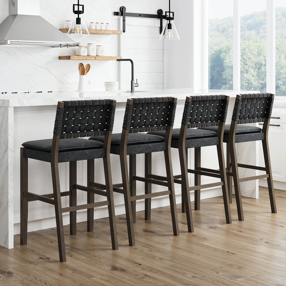Four wooden bar stools with black woven backrests and padded seats lined up at a white kitchen island.