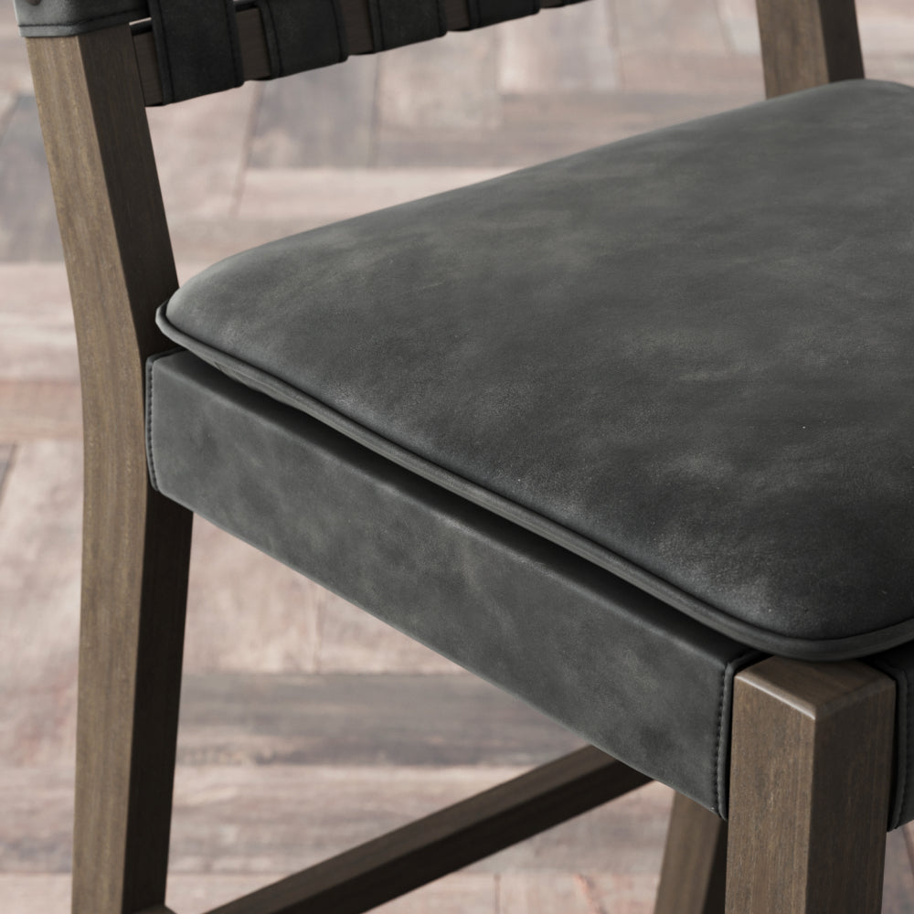 A wooden chair with a dark grey upholstered seat and a woven backrest.