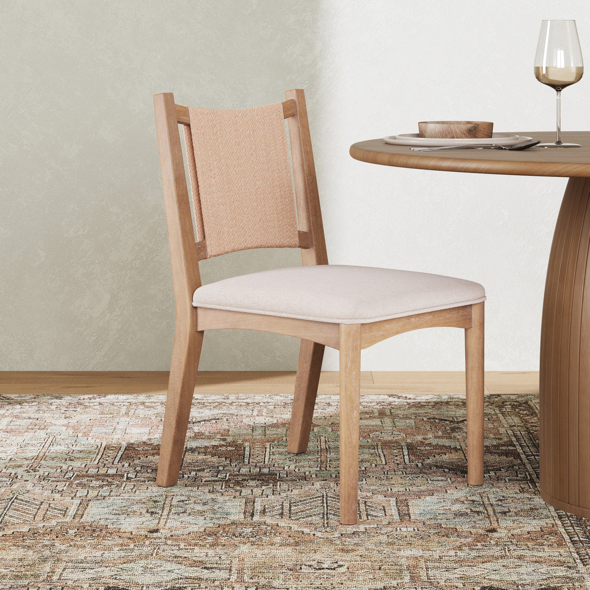 A wooden dining chair with a woven backrest and upholstered seat positioned next to a round wooden table.