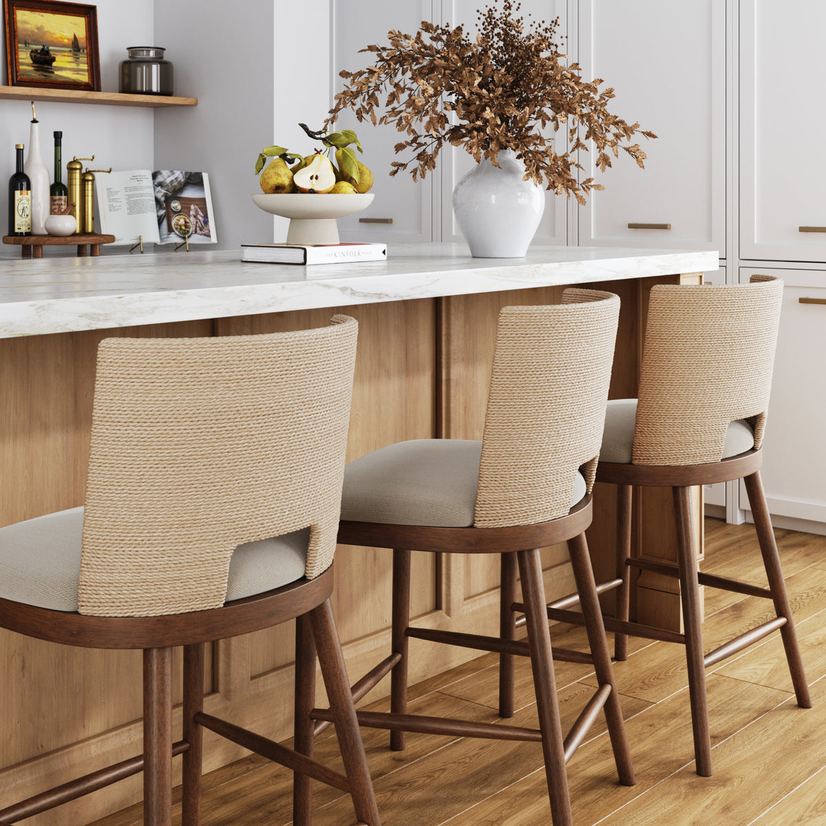 Three wooden bar stools with woven backs and light-colored cushions tucked under a kitchen island.