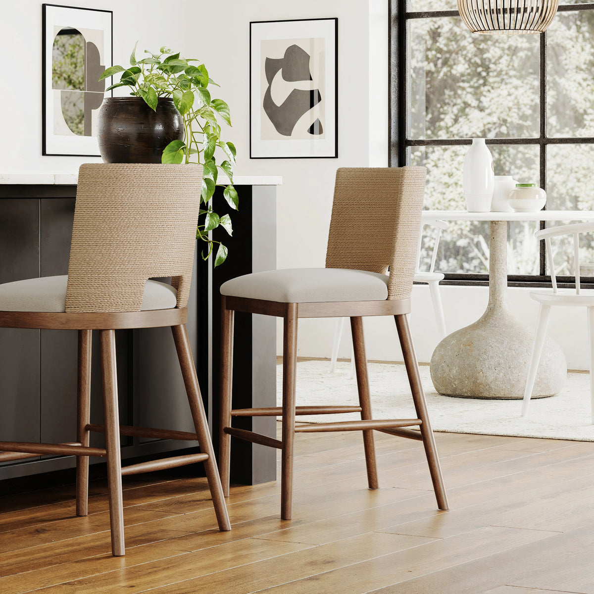 Two wooden bar stools with woven backs and light gray seats positioned at a kitchen island.