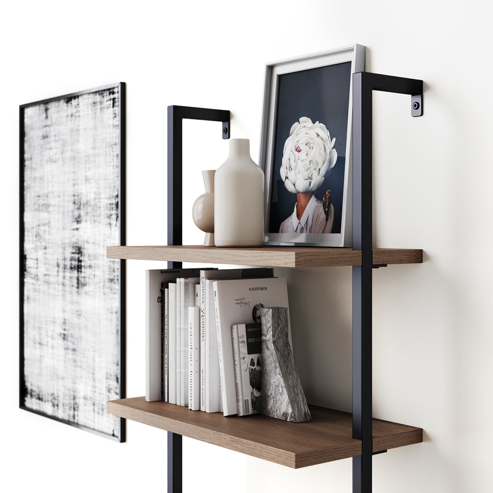 Two-tiered wall-mounted shelf with wooden shelves and black metal brackets, holding a picture frame, two vases, books, and a bookend.