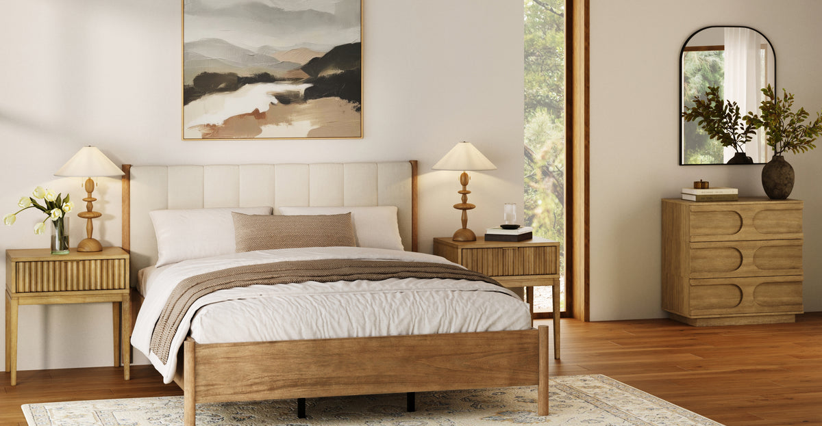 A bedroom with a wooden bed frame, two nightstands with lamps, a dresser with a mirror, and a landscape painting hanging above the bed.