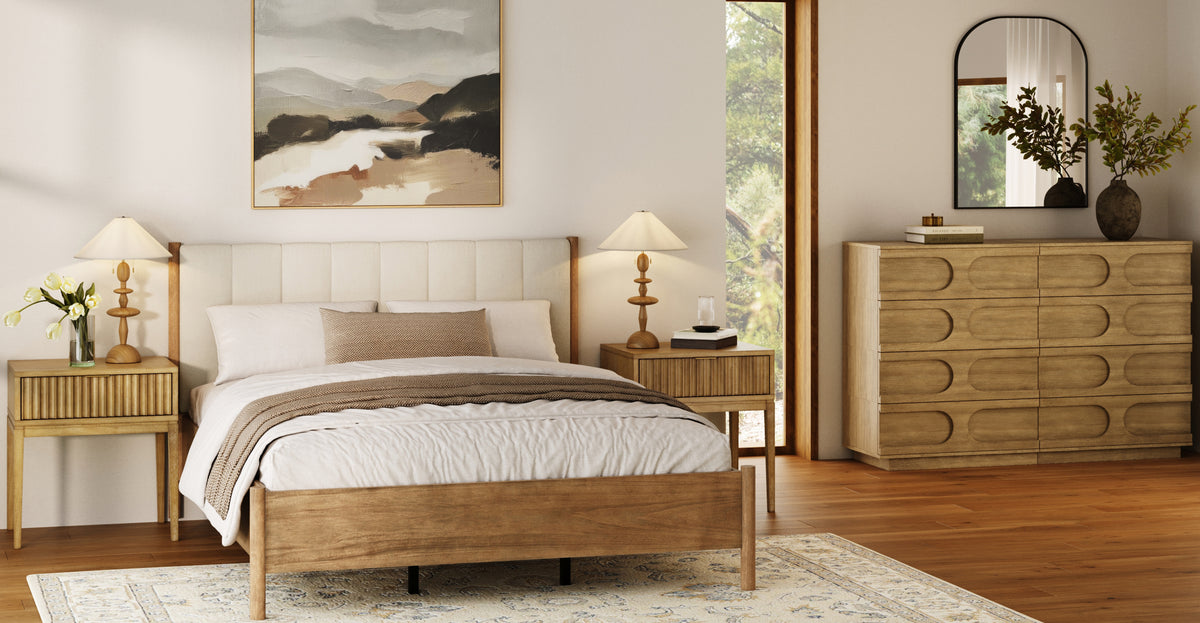 A bedroom featuring a wooden bed frame, two matching nightstands with lamps, a dresser with an arched mirror, and landscape wall art.