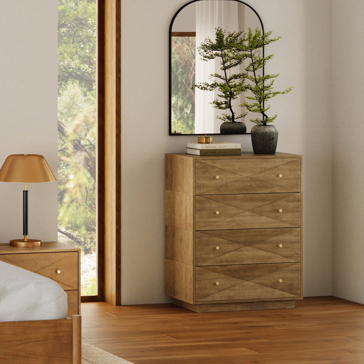 A wooden four-drawer dresser with a geometric pattern, topped with a potted plant and books, standing next to a mirror and a bedside table with a lamp.