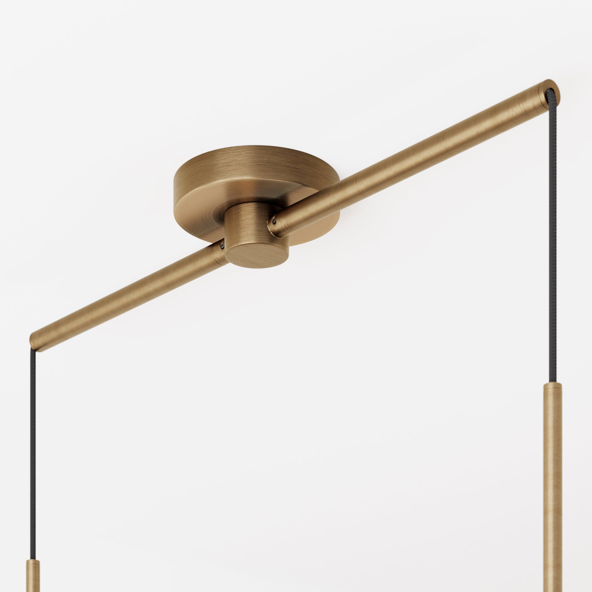 A close-up of a modern brass ceiling light fixture with a cylindrical base and a horizontal rod, from which two black cords hang downward against a white background.