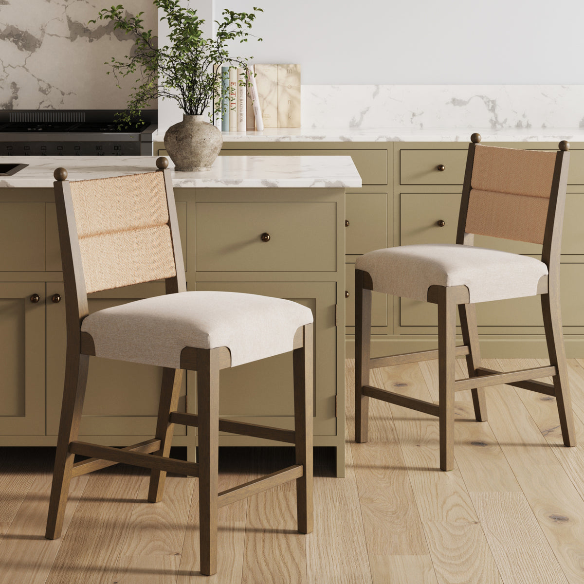 Two wooden counter stools with light fabric seats and woven cane backrests in a kitchen.