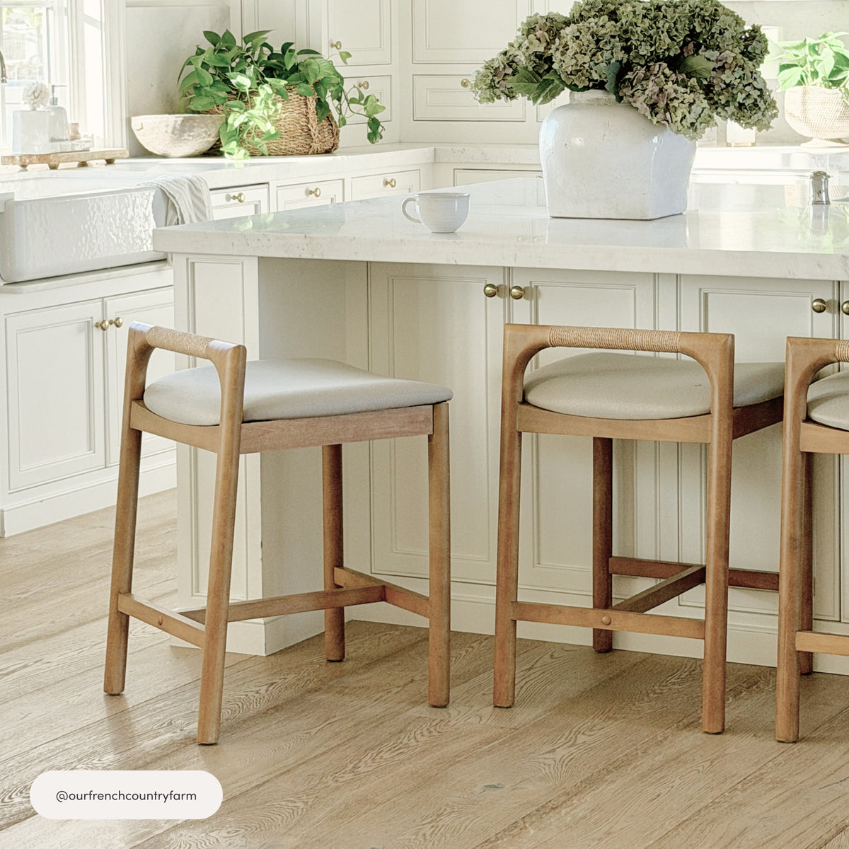Two Nathan James Modern Wooden Upholstered Low Back Counter Stool Light Brown units with light gray upholstered cushion seats and low, wrapped backs positioned at a kitchen island.