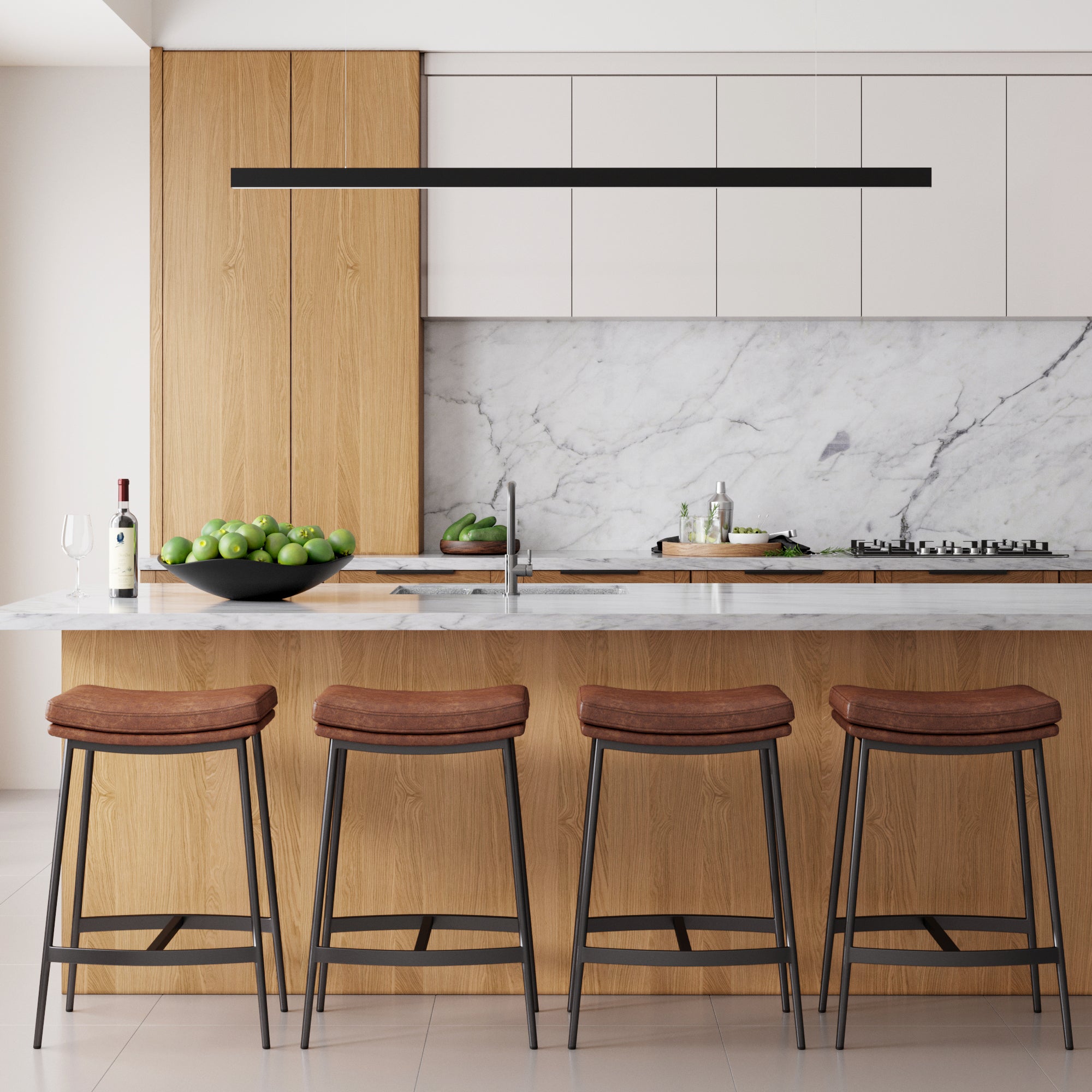Modern kitchen with a marble backsplash and island, wooden cabinets, four brown leather barstools, a bowl of green apples, a wine bottle and glass, and a sleek black pendant light overhead.