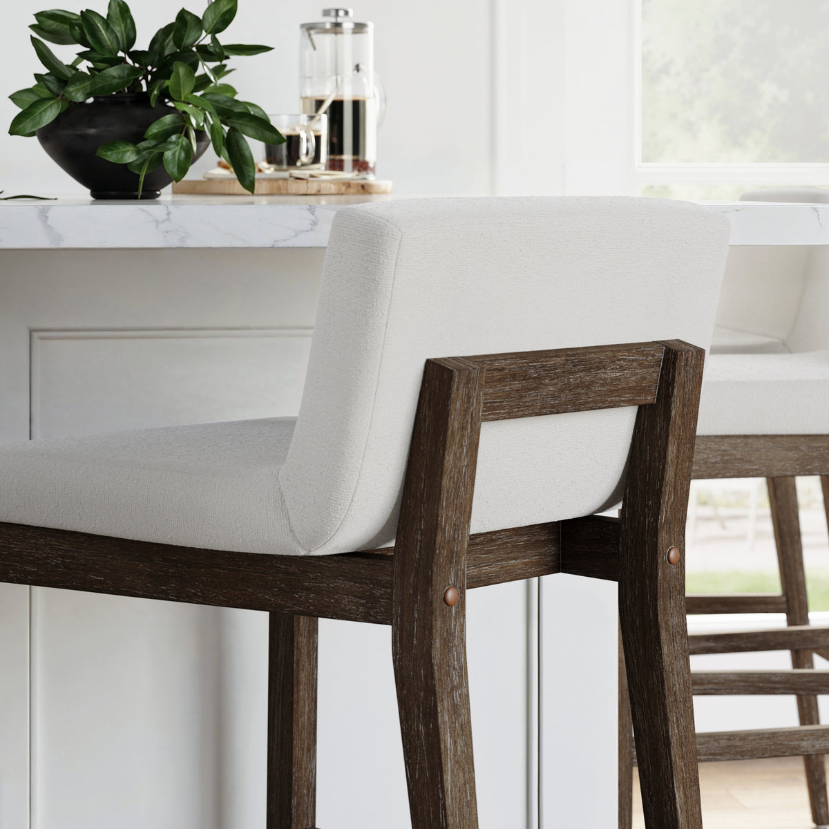 A wooden bar stool with an upholstered white seat, positioned at a marble kitchen island.