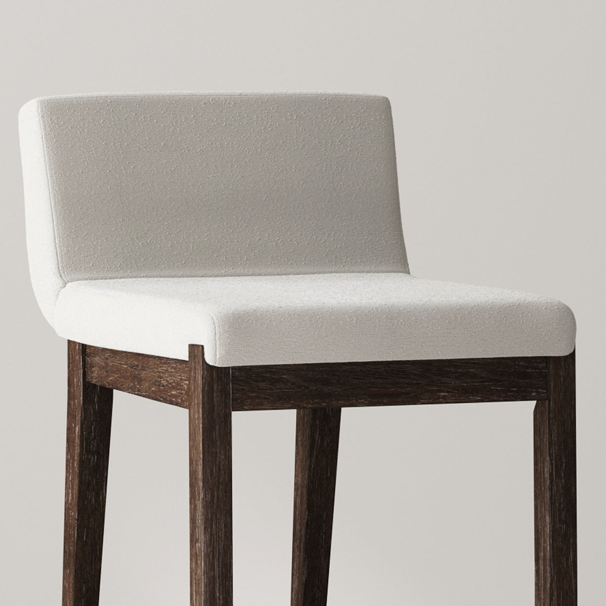 A backless bar stool with a white upholstered seat and dark wood legs.