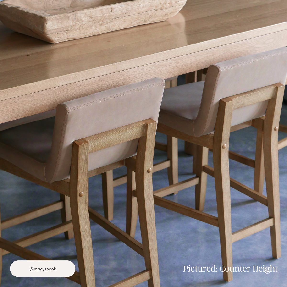 Two Nathan James Exposed Wood Back Bar Stools Light Brown with light-colored padded seats tucked under a wooden counter.
