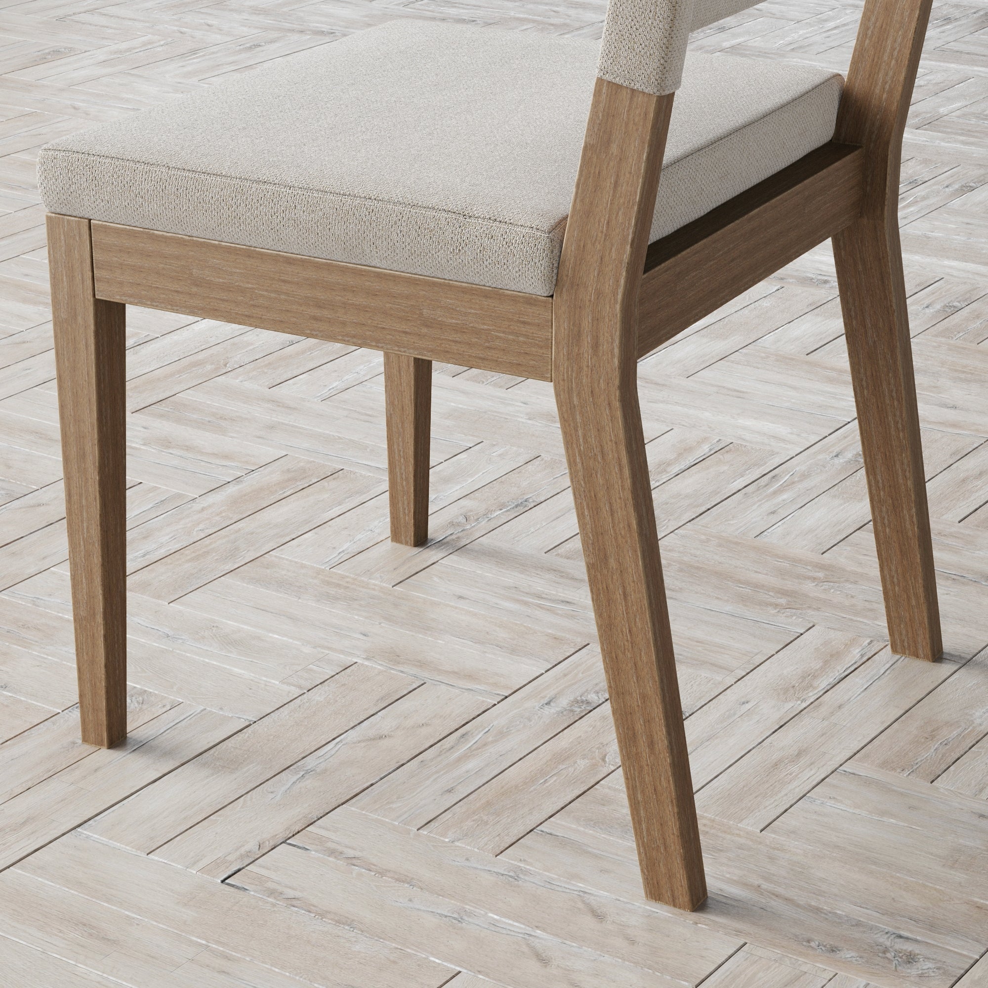 A close-up of a wooden chair with light beige fabric upholstery, shown on a light-colored, herringbone-patterned wooden floor. Only the back half of the chair is visible.