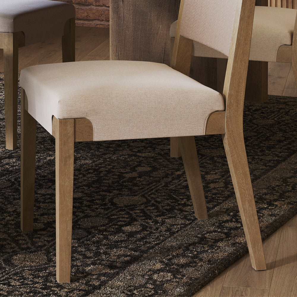 A wooden dining chair with a light-colored upholstered seat and backrest.