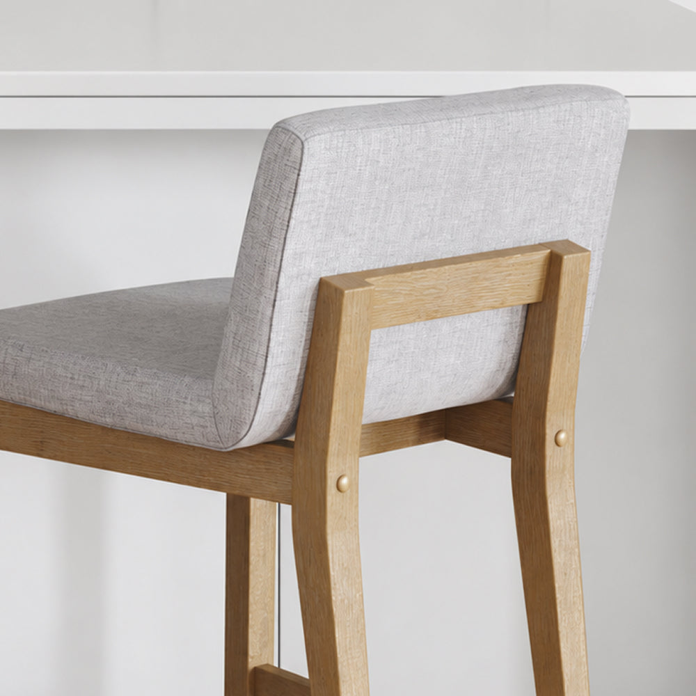 A bar stool with a light gray upholstered seat and backrest, supported by a wooden frame.