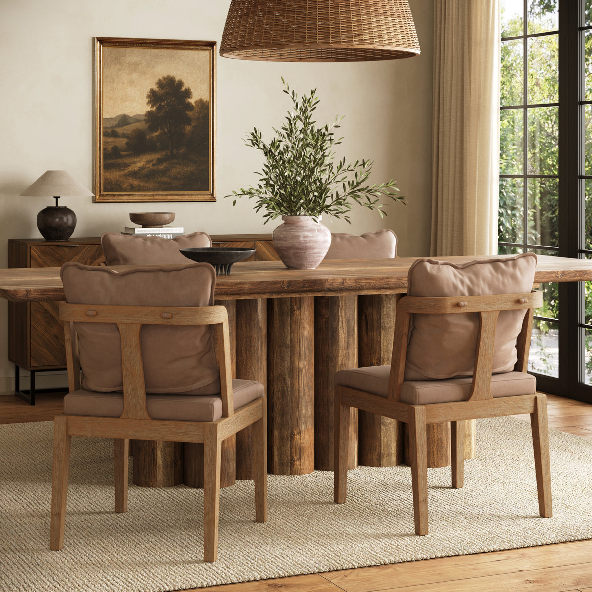 A wooden dining table with a cylindrical log base and four upholstered chairs, set in a dining room with a landscape painting and a hanging woven pendant light.