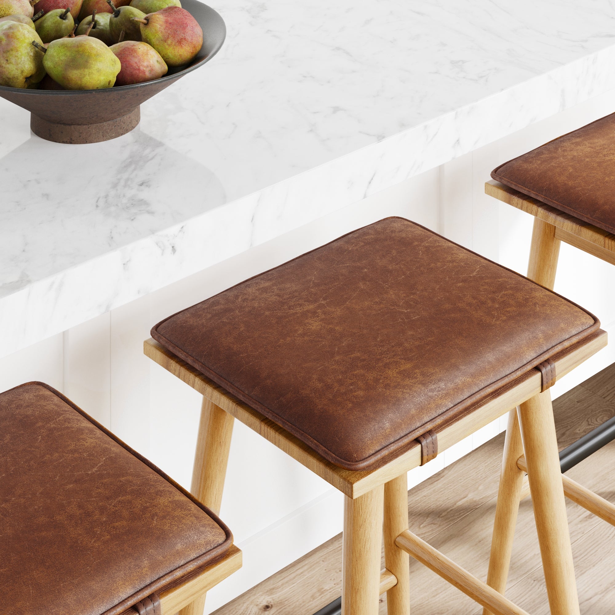 Three wooden bar stools with brown leather cushions are positioned next to a white marble countertop. A dark bowl filled with pears sits on the counter. The scene has a modern, clean look.