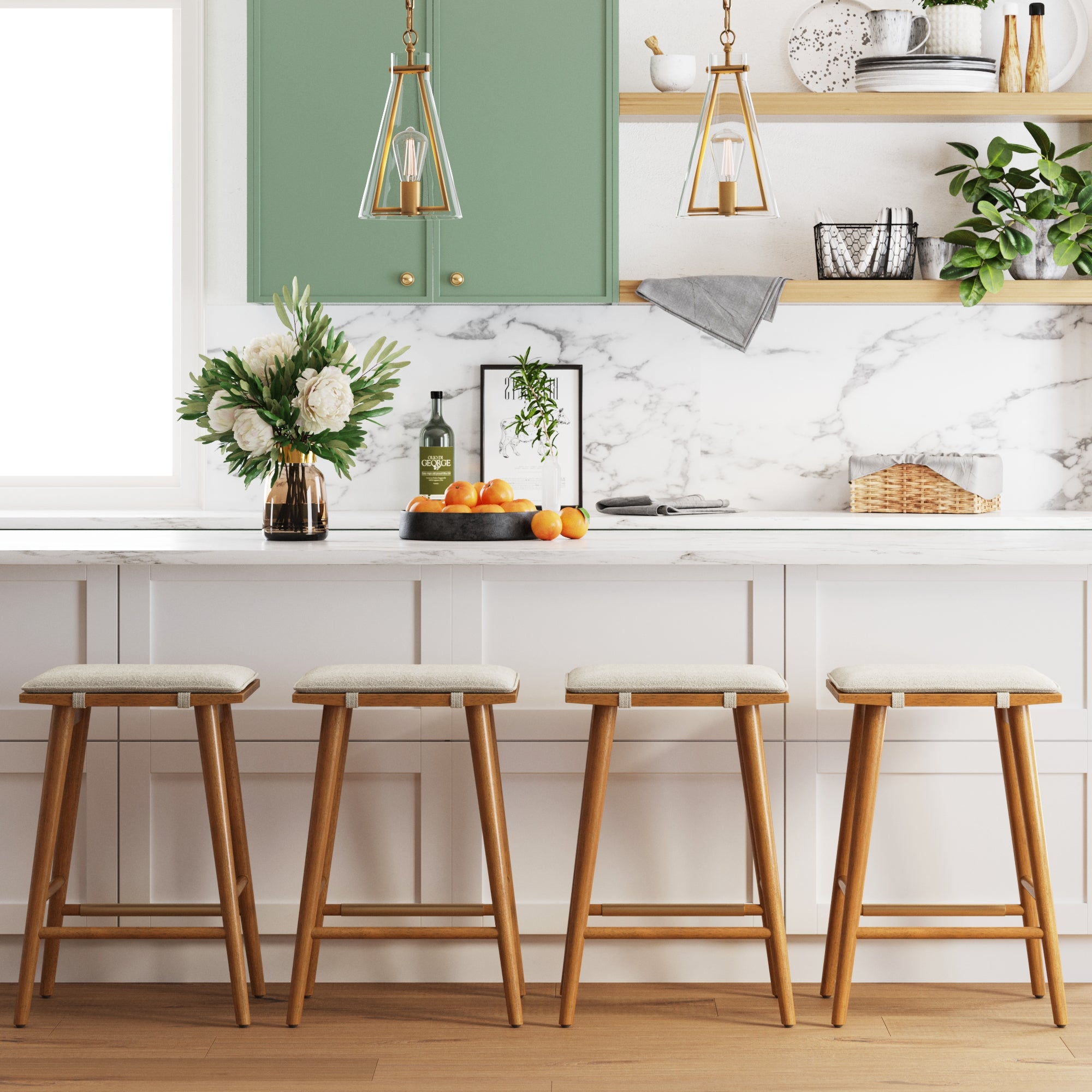 A modern kitchen with a marble countertop, four wooden stools, green cabinets, gold pendant lights, flowers in a vase, a bowl of oranges, and decorative items on wooden shelves.