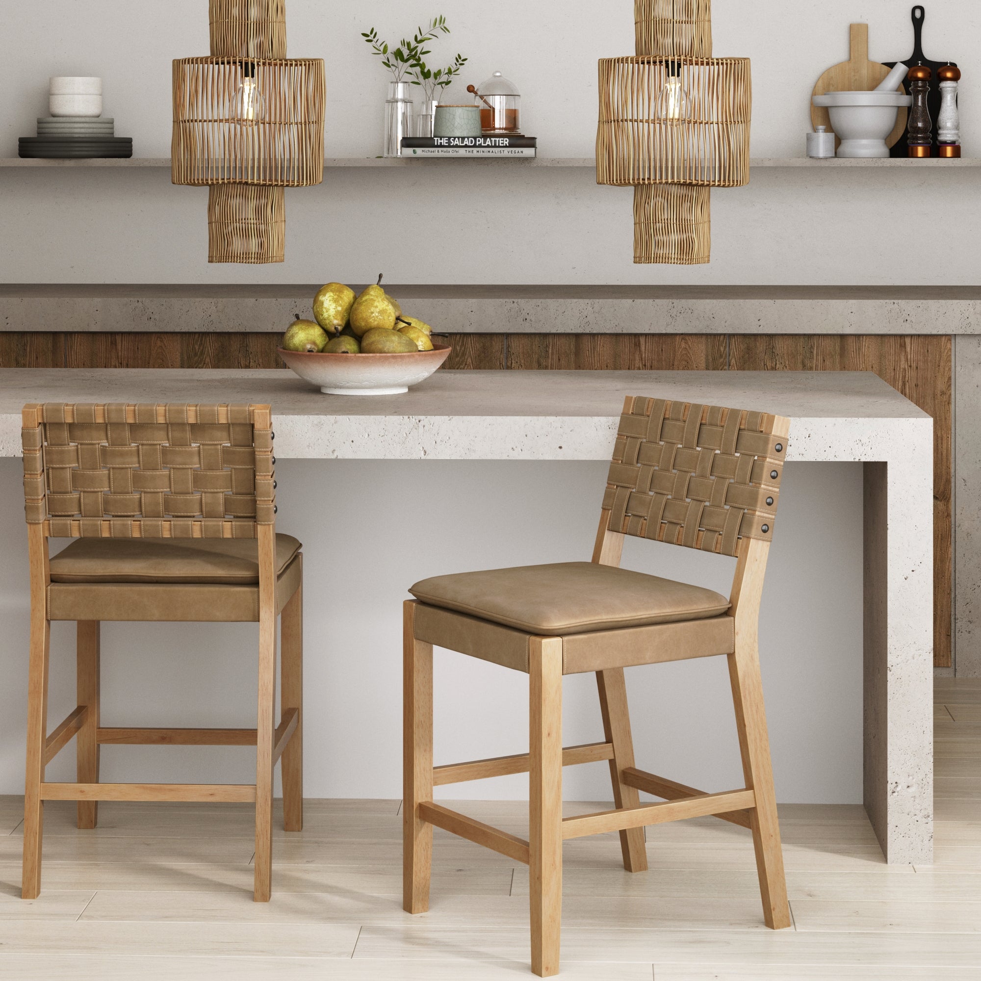 A modern kitchen features a white stone island with two wooden bar stools, a bowl of pears, woven pendant lights, and minimalist shelves with decor and kitchen items against a wood-accented wall.