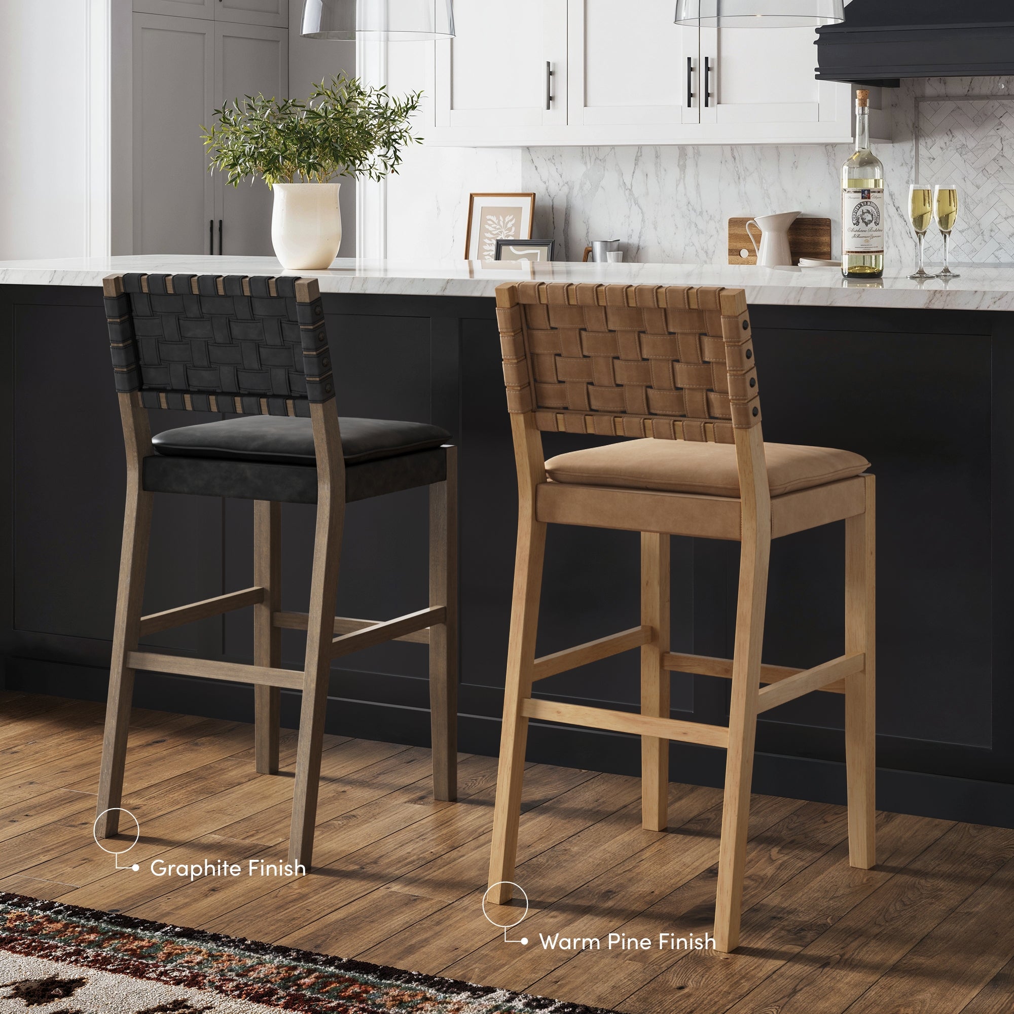 Two woven-back bar stools with wooden legs sit by a kitchen island. One stool has a black seat and back with a graphite finish, while the other has a tan seat and back with a warm pine finish. Kitchen decor appears in the background.