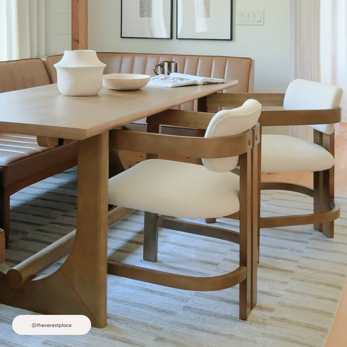 Two Nathan James Boucle Dining Chair w/ Curved Back and Arm Light Brown chairs with cream-colored curved backrests and seats positioned at a wooden dining table with a built-in tan bench.