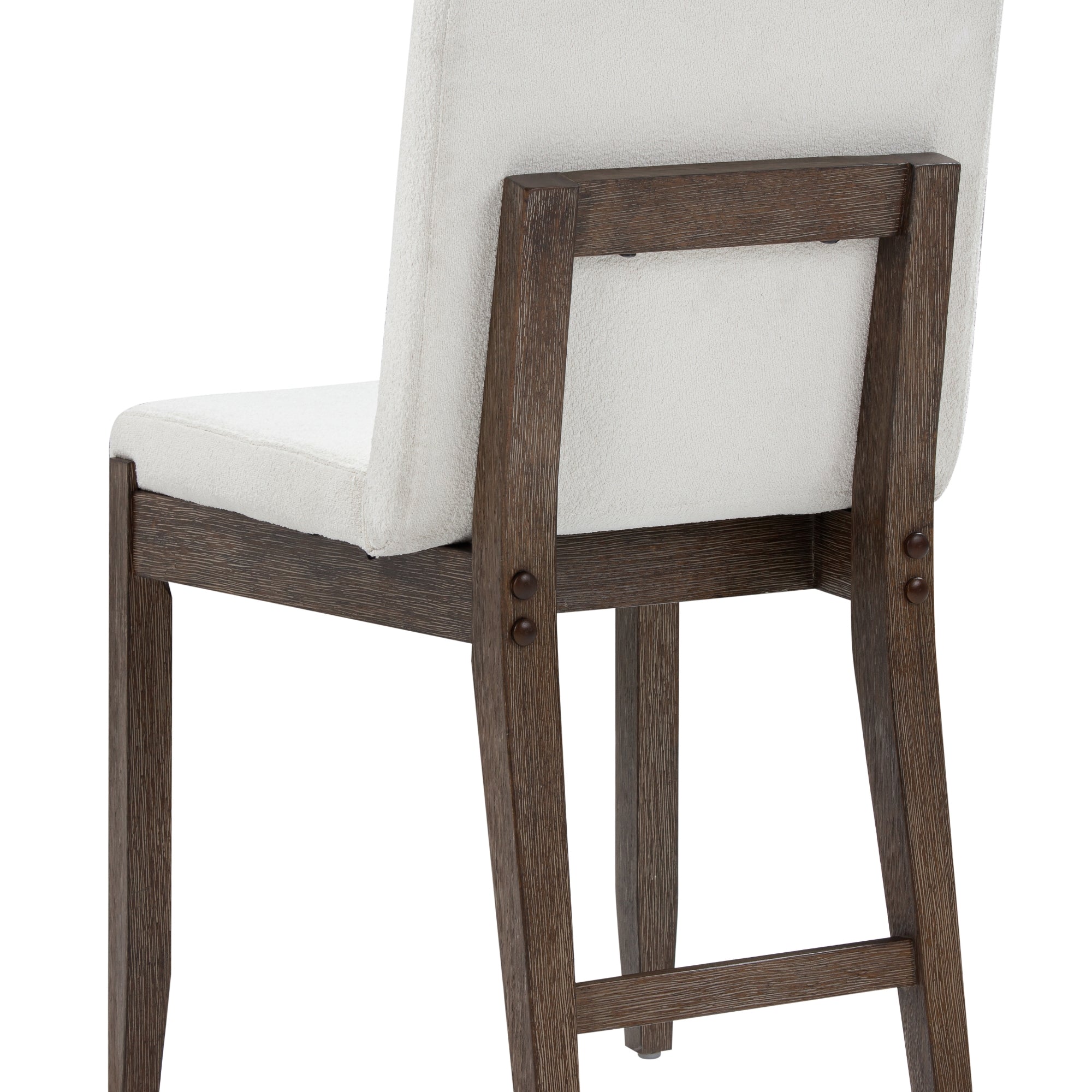 A close-up view of the back and legs of a wooden chair with a cushioned, light-colored upholstered seat and backrest. The wood has a dark finish and visible grain.