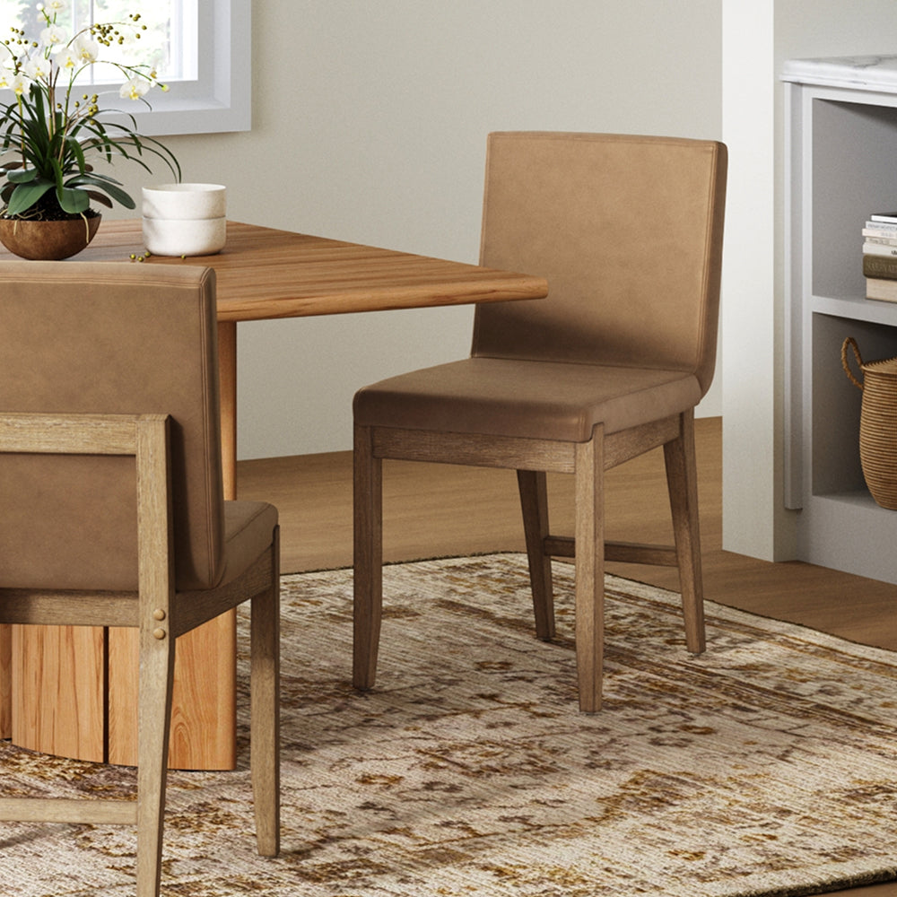 Two tan upholstered dining chairs with wooden legs positioned around a wooden dining table.