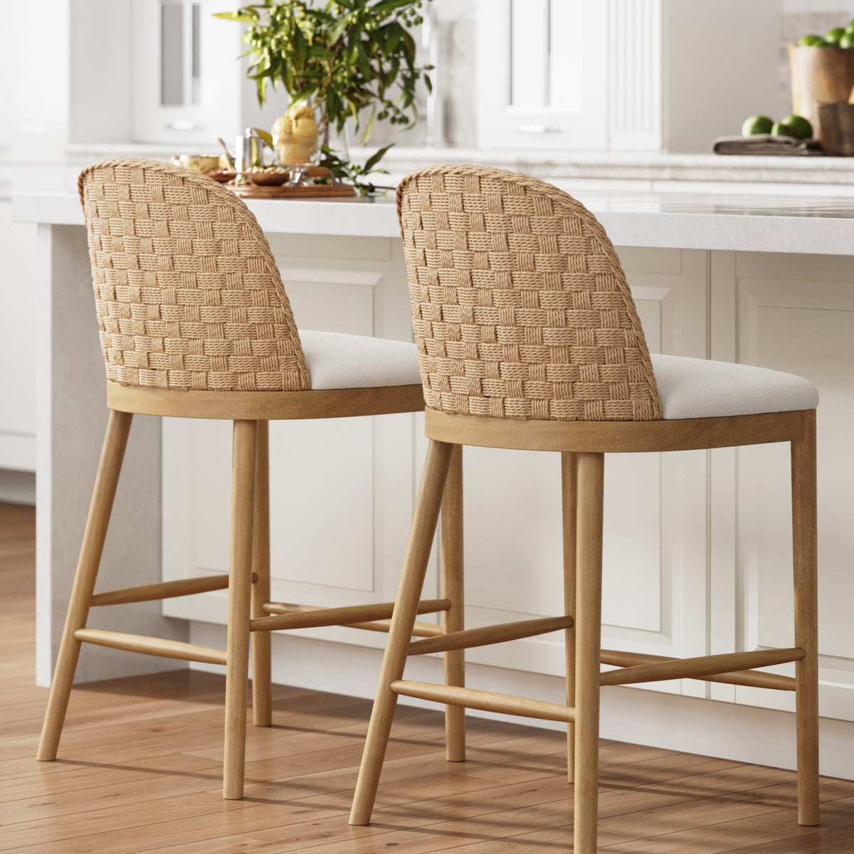 Two wooden counter stools with woven backrests and upholstered seats tucked under a kitchen island.