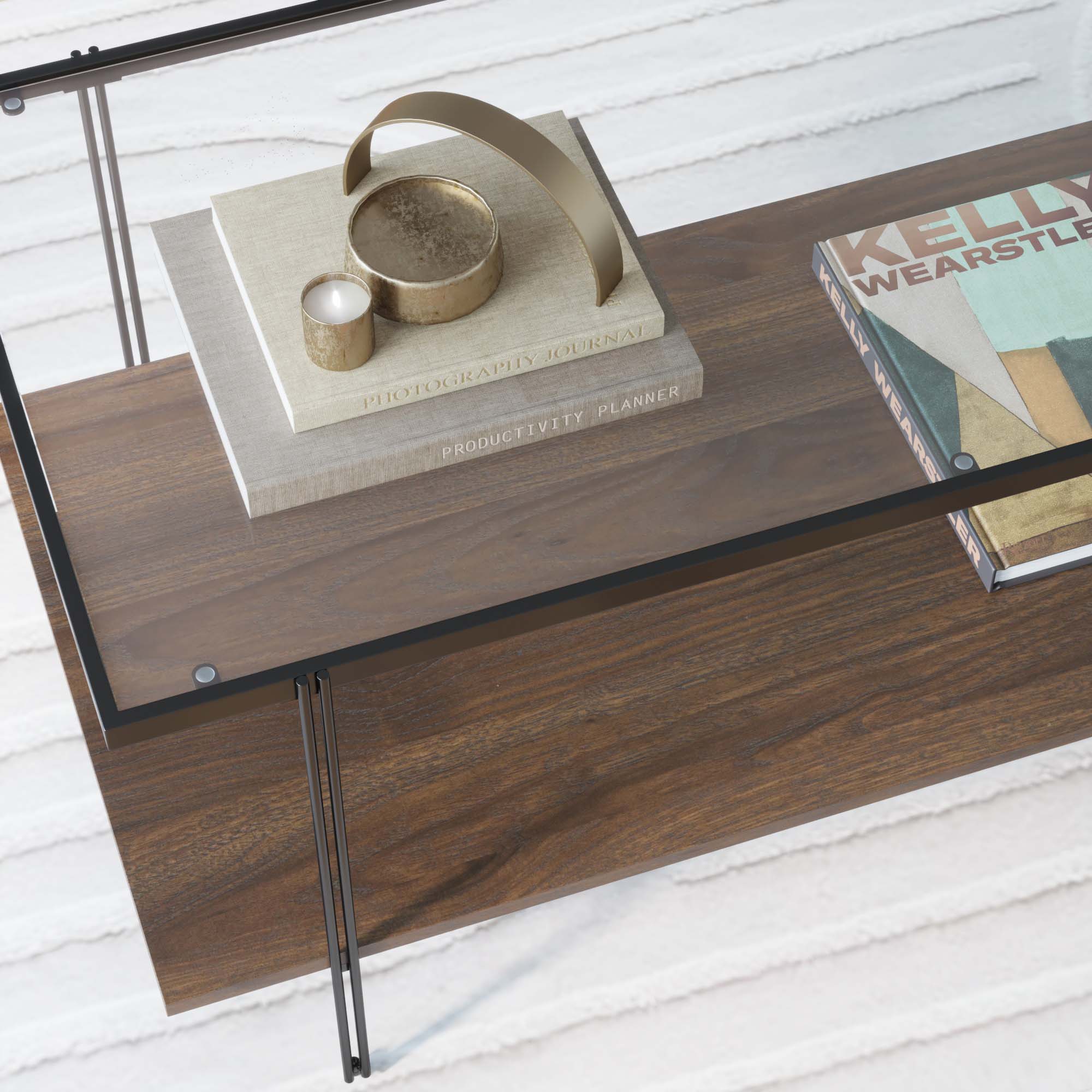 A wooden coffee table with a glass top holds stacked books, a gold decorative object, and two candles. One book is titled Productivity Planner, and another partially shows Kelly Wearstle. The table sits on a white rug.
