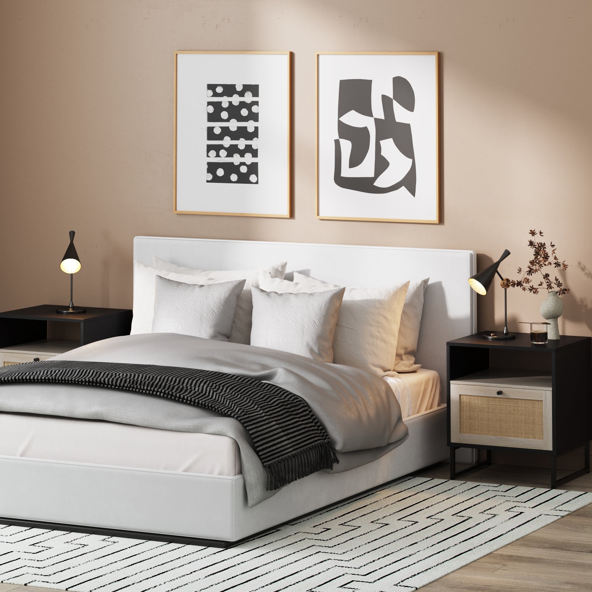 A modern bedroom with a white bed, gray and white bedding, black nightstands with lamps, abstract wall art above the bed, and a patterned rug on the floor. Dried flowers sit on the right nightstand.