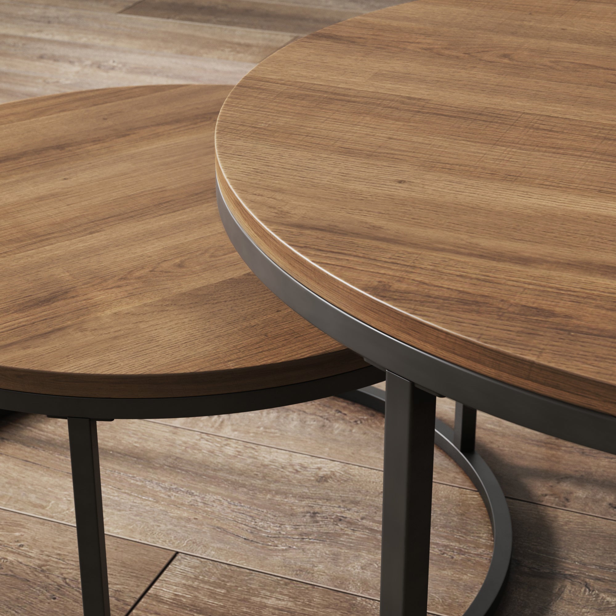 Two round wooden tables with black metal legs, positioned next to each other on a wooden floor. One table is slightly smaller and partially tucked under the larger table.