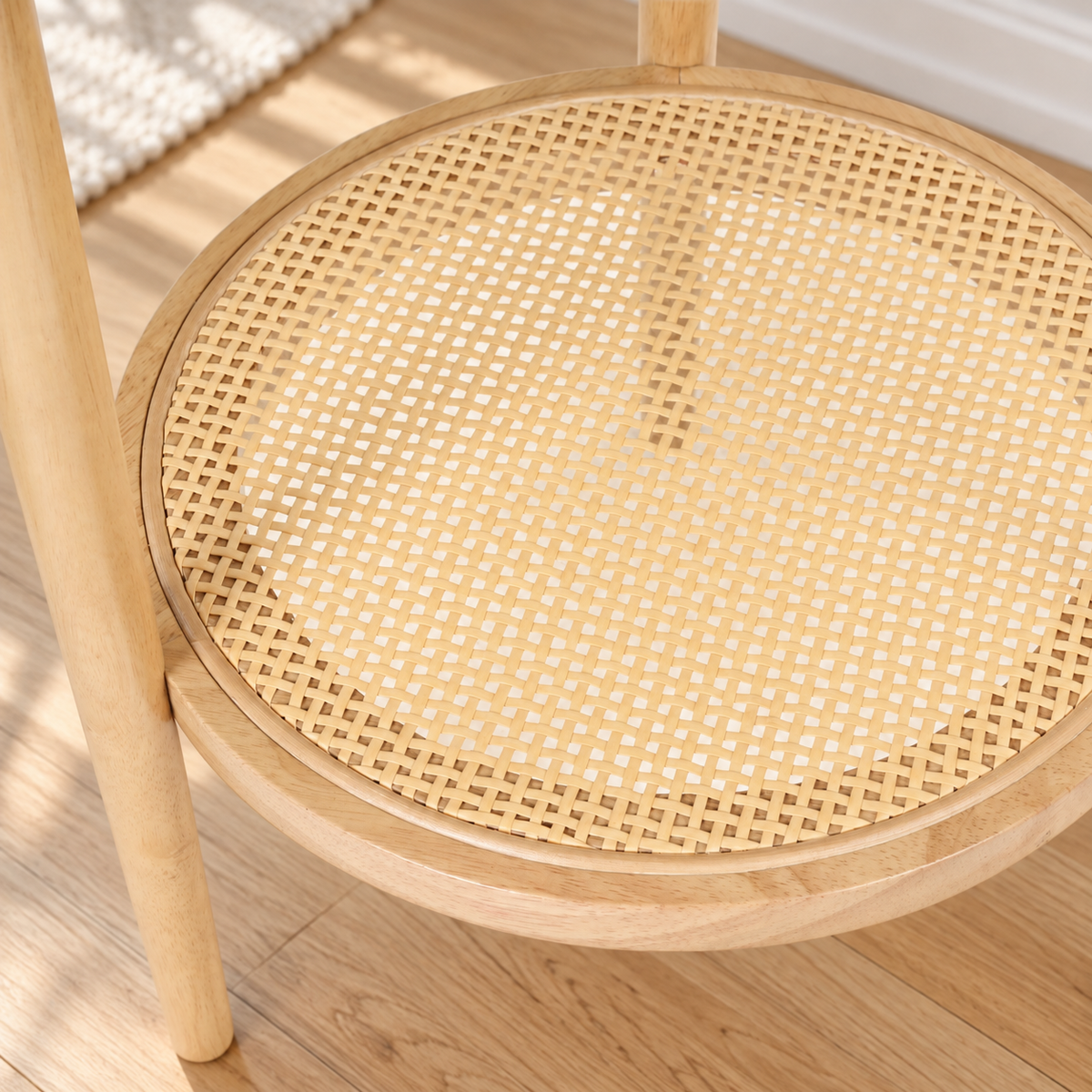 Round wooden side table with a woven cane shelf.