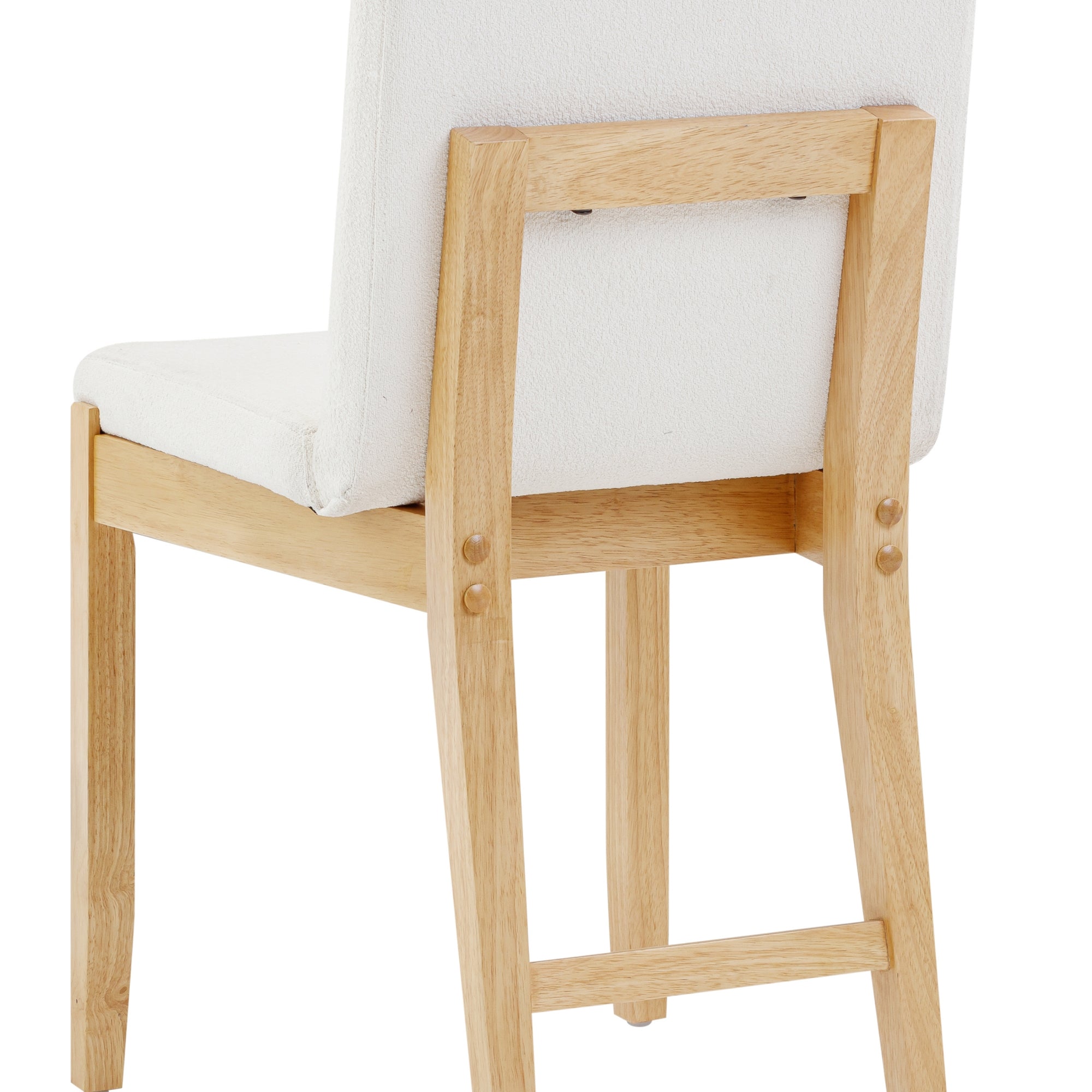 A close-up of the back and side of a wooden chair with a light-colored frame and a cushioned white seat and backrest.