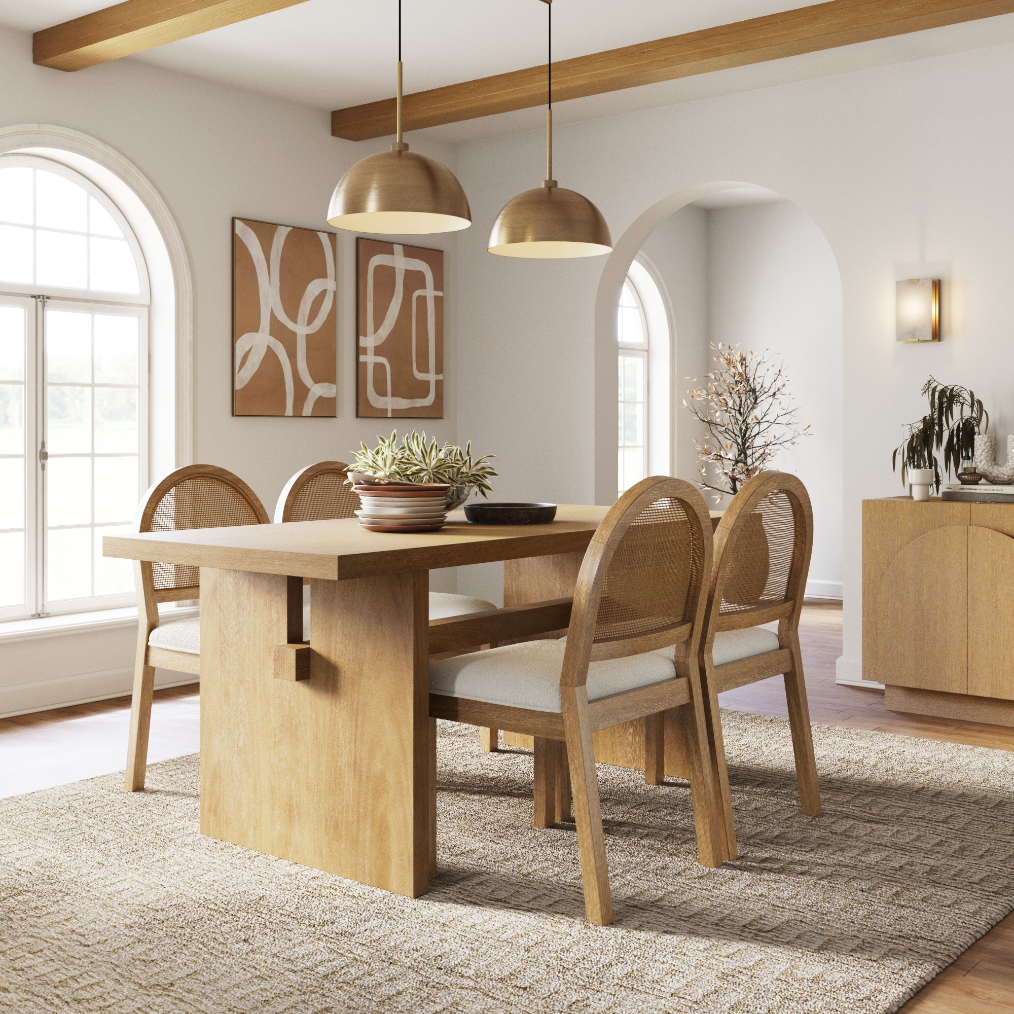 A modern dining room with a wooden table, four cushioned chairs, two pendant lights, abstract art on the wall, and large arched windows letting in natural light. A plant centerpiece decorates the table.
