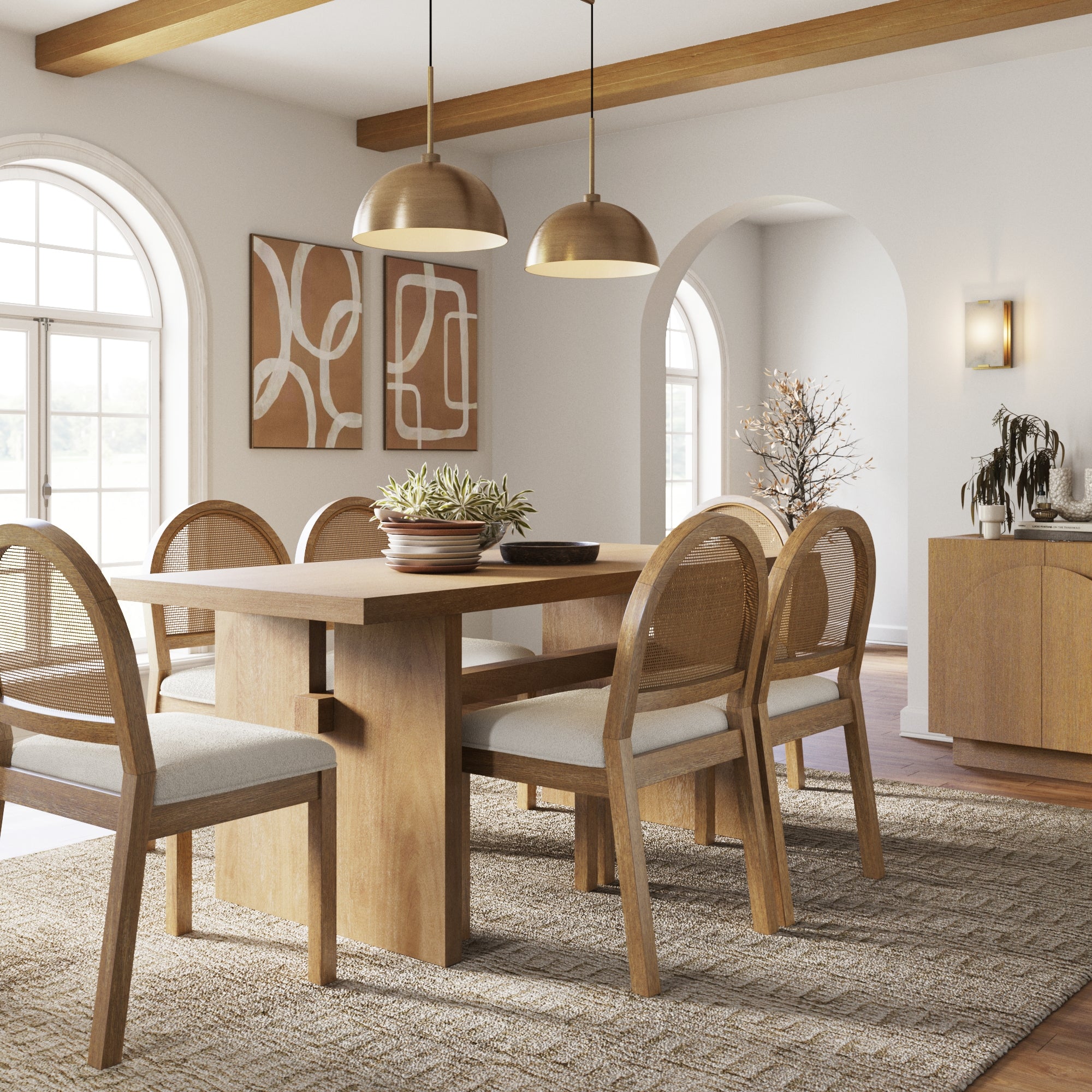 A modern dining room features the Nathan James Bohemian Cane Dining Set with six cushioned rattan chairs, a wood veneer table, pendant lights, abstract wall art, arched windows, and neutral décor atop a woven rug brightened by natural light.