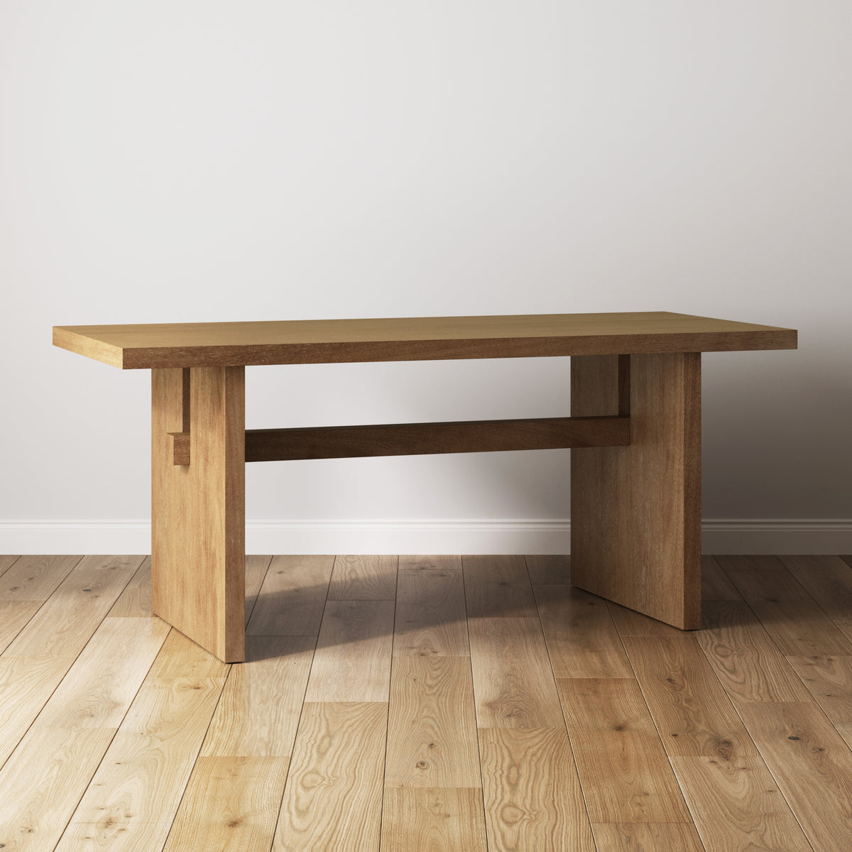A rectangular wooden table with thick legs and a sturdy design, placed on a wooden floor against a plain white wall in a well-lit room.