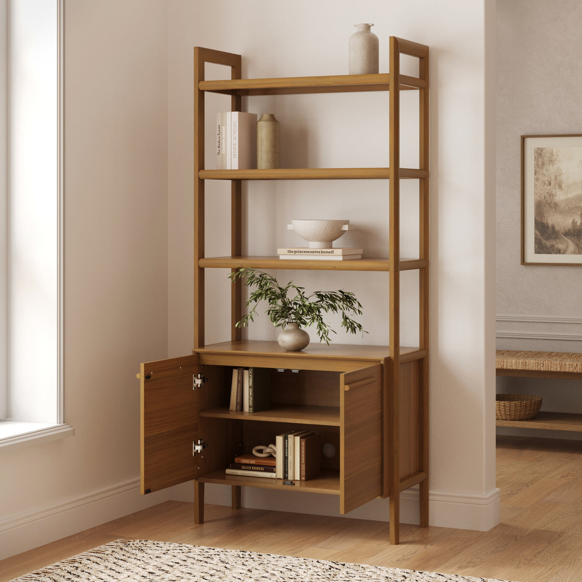 Tall wooden bookshelf with five open shelves and a cabinet at the base with two open doors, styled with decorative vases, greenery, and books.